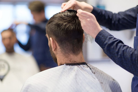 理发店理发摄影照片_美容、理发和人的概念—男性客户和理发师在理发店理发。理发店理发师理发
