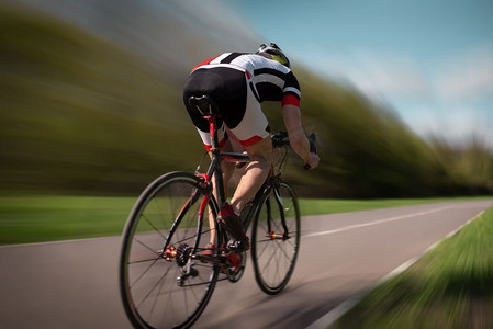 骑自行车的头盔和运动服骑自行车，速度效果，后视图。在自行车道上锻炼，骑自行车