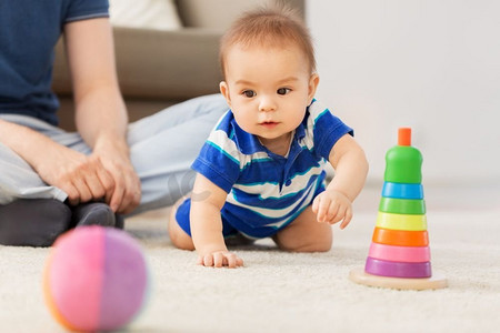 家庭，父亲和童年的概念—快乐的男婴与父亲和玩具金字塔在家里。男孩与父亲和金字塔玩具在家里