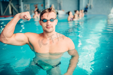 运动游泳运动员显示肌肉，室内游泳池。水上运动。竞技游泳运动员展示肌肉，水上运动
