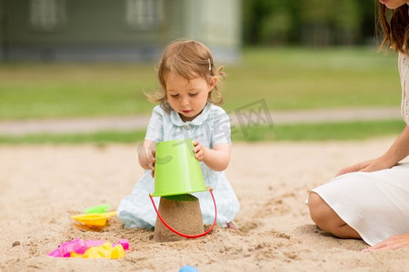 小铲子摄影照片_童年、休闲与人的概念--小女婴在沙盒里玩玩具。小女婴在沙盒里玩玩具