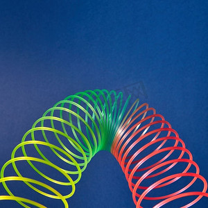 柔性彩虹塑料弹簧，抛物线形式，蓝色背景，文字位置。几何抛物线从有色时髦玩具。