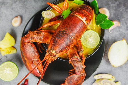 盘子摄影照片_红龙虾辣汤碗/熟海鲜龙虾餐桌和香料成分在黑色盘子泰国食物，冬阴功孔 