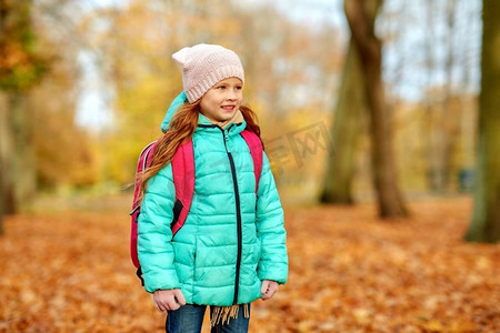 学校、教育和季节概念-秋季公园书包快乐的女学生。秋天公园里背着书包的快乐女学生