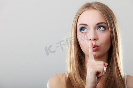 特写镜头妇女要求沉默或秘密与手指在嘴唇安静手势，在灰色背景