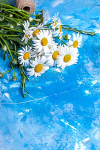 彩绘花卉摄影照片_夏季花卉卡片与洋甘菊与蓝色复古彩绘木质背景。