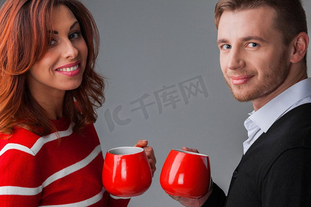 情侣手持红色咖啡杯的肖像，圣诞节或情人节概念。搭配红色咖啡杯
