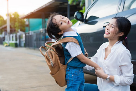 妈妈在早上上学前送淘气的男孩。幸福的家庭和生活方式的概念。教育和返校主题。