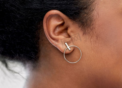 简约珠宝首饰摄影照片_珠宝，穿孔和人的概念—非裔美国人妇女耳朵特写镜头与银耳环。特写非洲妇女耳朵与耳环