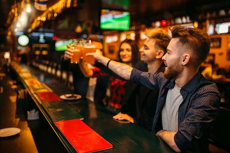 胜利摄影照片_在一家体育酒吧里，快乐的球迷们举起酒杯，举起啤酒，庆祝胜利