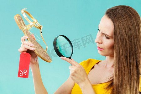 好的夏季购物理念时尚的女人选择鞋通过放大镜搜索，折扣红色标签与百分标志在手