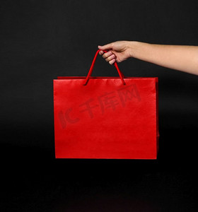 销售，消费主义和出口概念手拿红色购物袋在黑色背景手拿红色购物袋在黑色背景