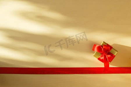 蝴蝶结边框摄影照片_假期，现在的概念。小金盒，礼品系装饰蝴蝶结，红丝带边框