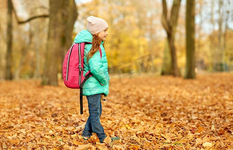 学校、教育和季节概念-秋季公园书包快乐的女学生。秋天公园里背着书包的快乐女学生