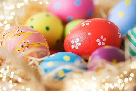 复活节，假日，传统和对象概念—关闭彩色鸡蛋在稻草。关闭彩色复活节彩蛋在稻草