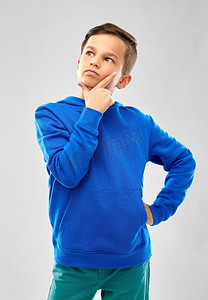 童年，表达和灵感概念—思考的男孩在灰色背景的蓝色连帽衫穿着蓝色连帽衫的思考男孩