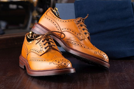 棕色全粒面皮革布洛克在木制显示在男鞋精品店与盒子和布鞋袋。男士鞋业精品店