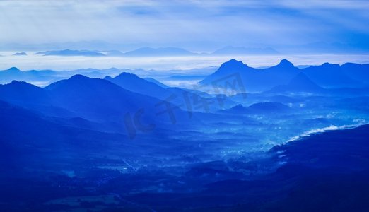 风景山有雾蓝天和升起的太阳在上午在小山—剪影蓝色山脉背景