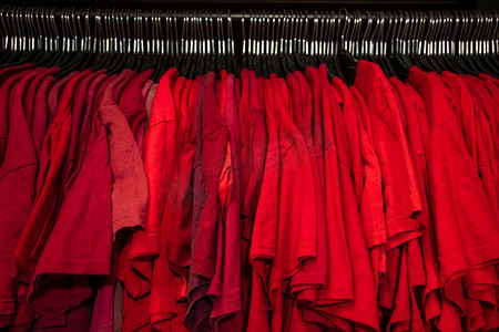 零售摄影照片_红色T恤在衣架上的商店衣柜衣柜栏杆