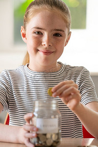 女孩把硬币放进玻璃罐子里的肖像，上面标着家里的储蓄