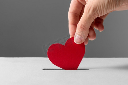 慈善、爱与情人节概念—近距离把红心放进募捐箱。’手把红心放进募捐箱
