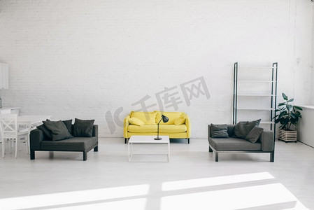 现代客厅内部有白色、黑色和黄色的色调，没有人。舒适的休息区，配有沙发、咖啡桌和空架子，舒适的家设计