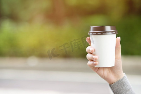  手拿纸杯带走喝咖啡在自然的早晨阳光。空格放置您的文本或徽标。	