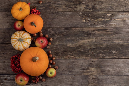 秋收静物以南瓜、苹果、榛子为木质背景，俯瞰。木桌上的秋收