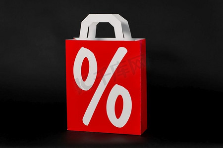 销售、消费主义和奥特莱斯概念--黑色背景下带有百分号的红色购物袋。带百分号的红色购物袋
