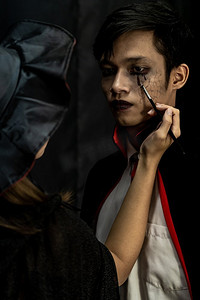 化妆艺术家做Asain青少年化妆万圣节服装作为吸血鬼准备万圣节派对狂欢节 