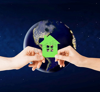 生态，环境和家园概念—手拿着绿色的房子在地球上的行星在太空。在太空中，手握着地球上的温室