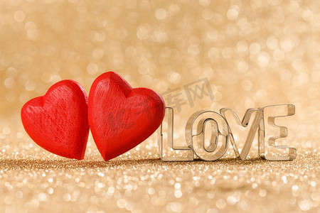 两个红色手工木心和字爱在金色明亮的闪光灯bokeh背景。红色的心在闪光背景