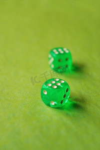 一个充满活力的单色微距，景深约为两个绿色玻璃赌博骰子，绿色背景上有两个幸运数字六。