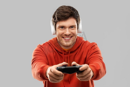 技术，游戏和人的概念—年轻人或游戏者在耳机与游戏手柄玩视频游戏。男子与游戏手柄玩视频游戏