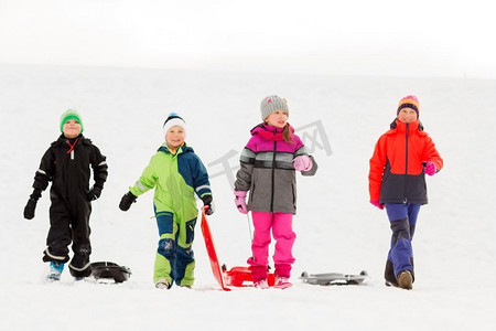 童年、雪橇和季节概念-一群快乐的小朋友在冬天拉雪橇。冬天玩雪橇的快乐小朋友