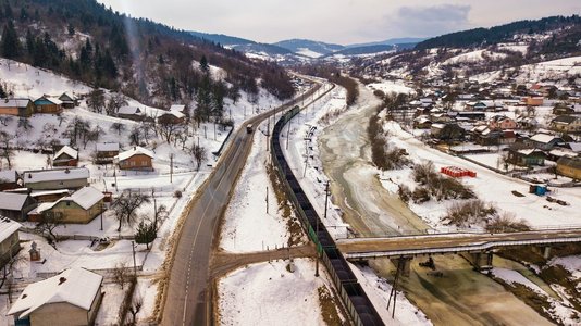 冬季旅行摄影照片_冬季旅行。火车和公共汽车在冬谷移动。鸟瞰德涅斯特河在喀尔巴阡山脉。
