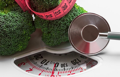饮食健康饮食体重控制概念。特写绿色花椰菜与卷尺和听诊器在白色鳞片