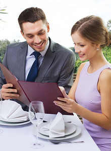 约会，奢侈品和人的概念—愉快的夫妇有菜单在餐馆在夏天背景一对夫妇与菜单在餐厅