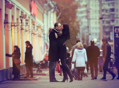 恋人亲吻和拥抱在一个城市街道与路人