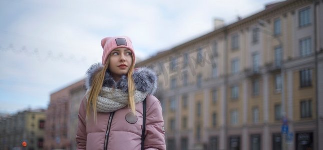 冬天街道摄影照片_一个穿着粉色夹克的女孩在冬天走在城市里