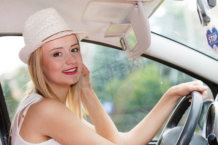 分心的司机。年轻的有吸引力的女人看着镜子，而开车。分心的女人驾驶她的车在镜子里看