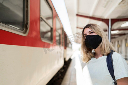 妇女戴着织物面具站立火车