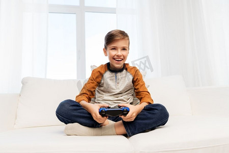 游戏，技术和人的概念—微笑的男孩与游戏手柄玩视频游戏在家里。快乐的男孩与游戏手柄玩视频游戏在家里