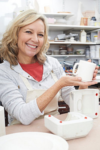 肖像的成熟女人在陶器工作室铸造杯子