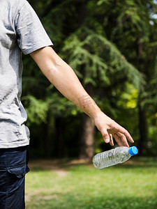 奥林巴斯数码相机。男子手摇塑料水瓶公园