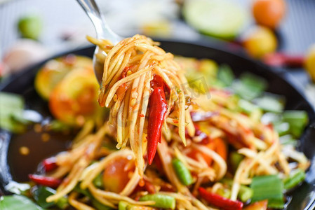 在叉子上的木瓜沙拉/绿色木瓜沙拉辛辣的泰国食物在桌子上的焦点—Som tum Thai