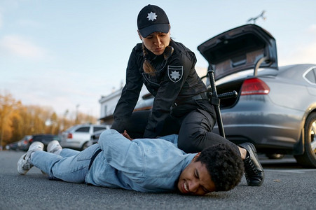 女警官在制服逮捕可疑的年轻汽车司机拧回他的手。警方拘捕可疑青年司机