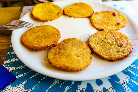 酥脆锅巴土豆摄影照片_六个圆形美味的土豆煎饼在白色盘子。详细的食物关闭六个土豆煎饼