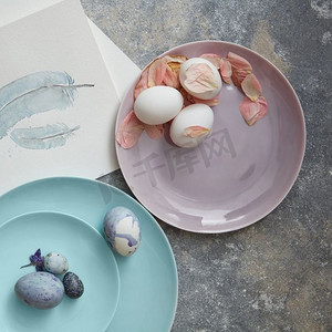 自制复活节彩蛋在一个盘子与玫瑰花瓣在石头背景平躺。自制的复活节彩蛋
