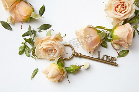白色背景上的古董钥匙和美丽的玫瑰花蕾。玫瑰花瓣钥匙